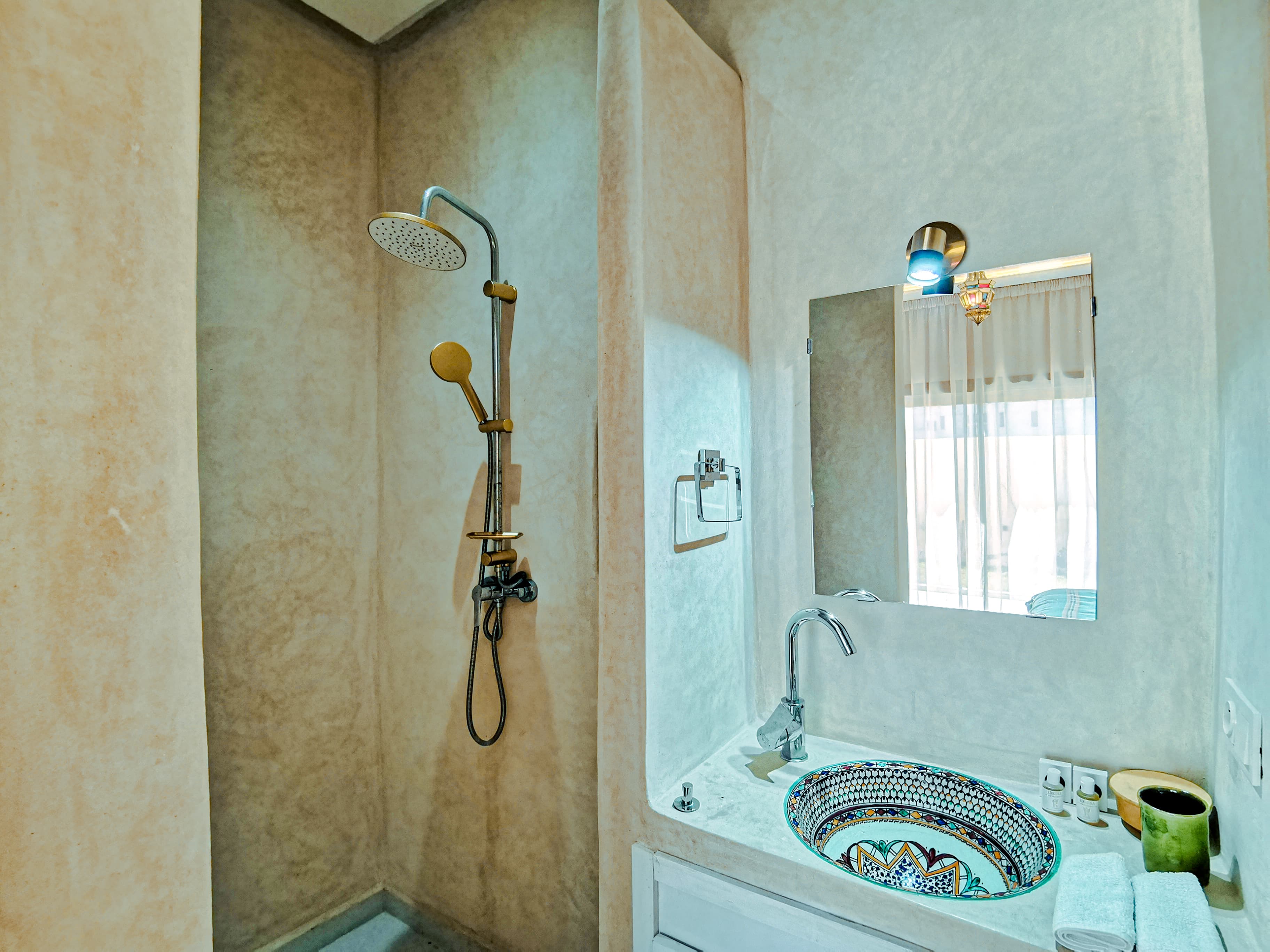 Bathroom with patterned sink and gold shower